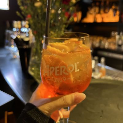 Eine Frau genießt einen Aperol-Spritz in abendlicher Atmosphäre