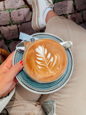 Junge Frau hält eine Tasse Cappuccino mit cremigem Schaum